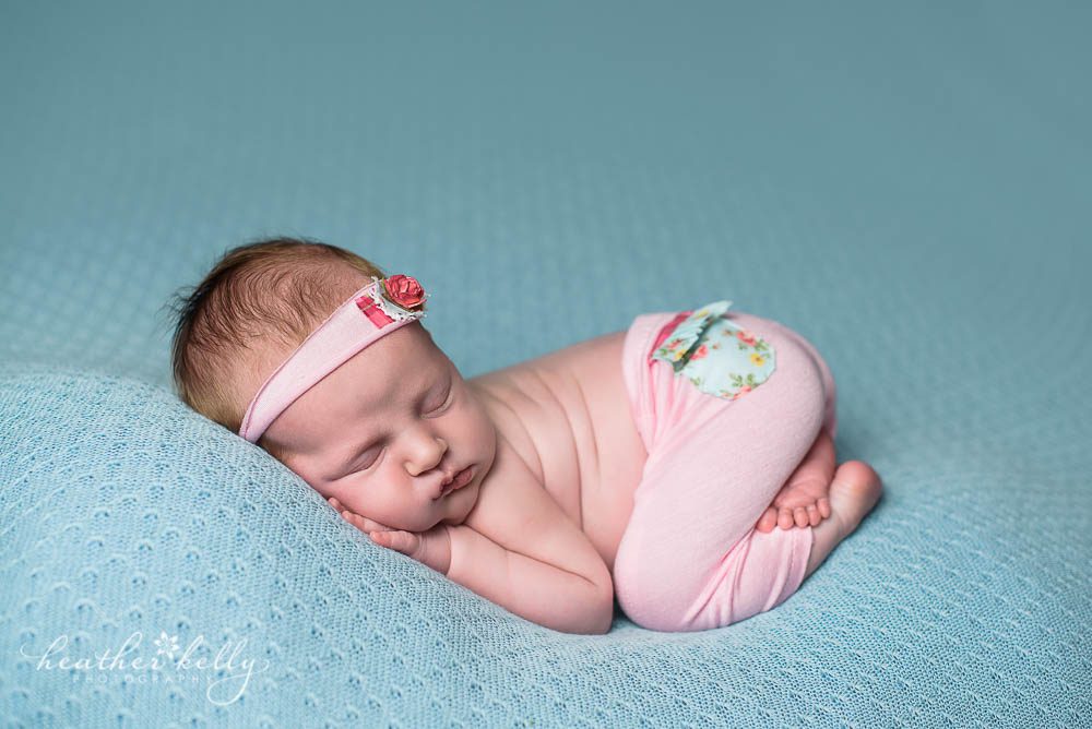 newborn girl with pink pants on blue blanket