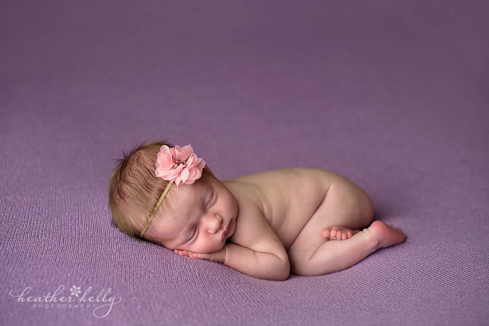 naked newborn girl on lavender blanket with pink headband