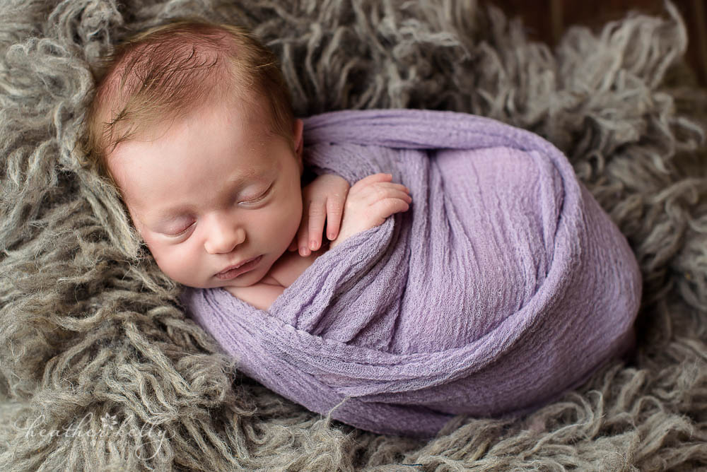 baby girl with lavender wrap on gray flokati