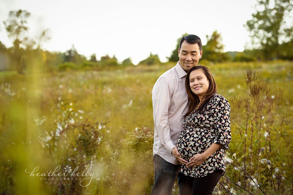 maternity photo with mom and dad in field