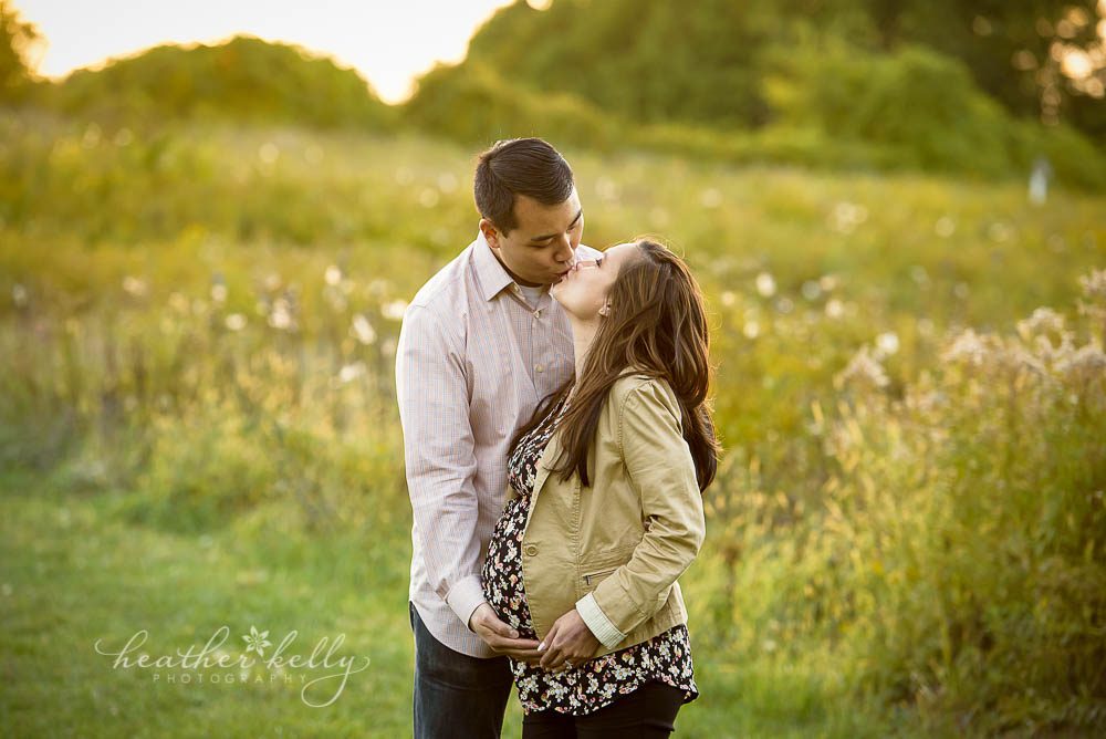 mom and dad to be kissing in field