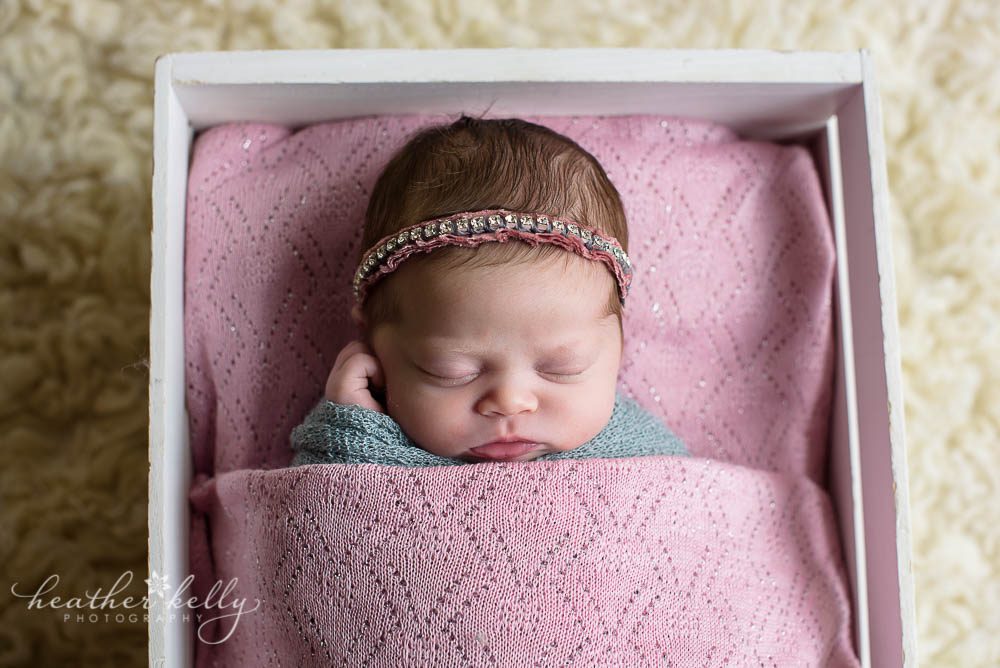 baby girl wrapped and tucked in crate with blanket newborn blog circle