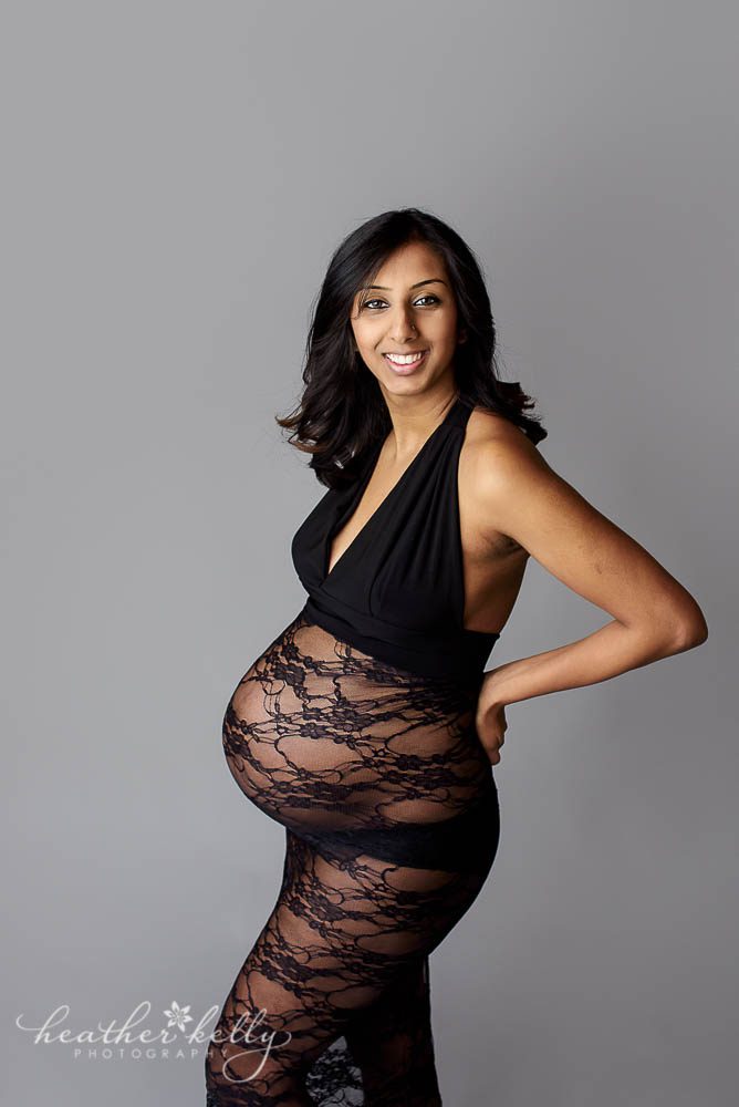 maternity photos of mom on gray background with black lace pregnancy gown