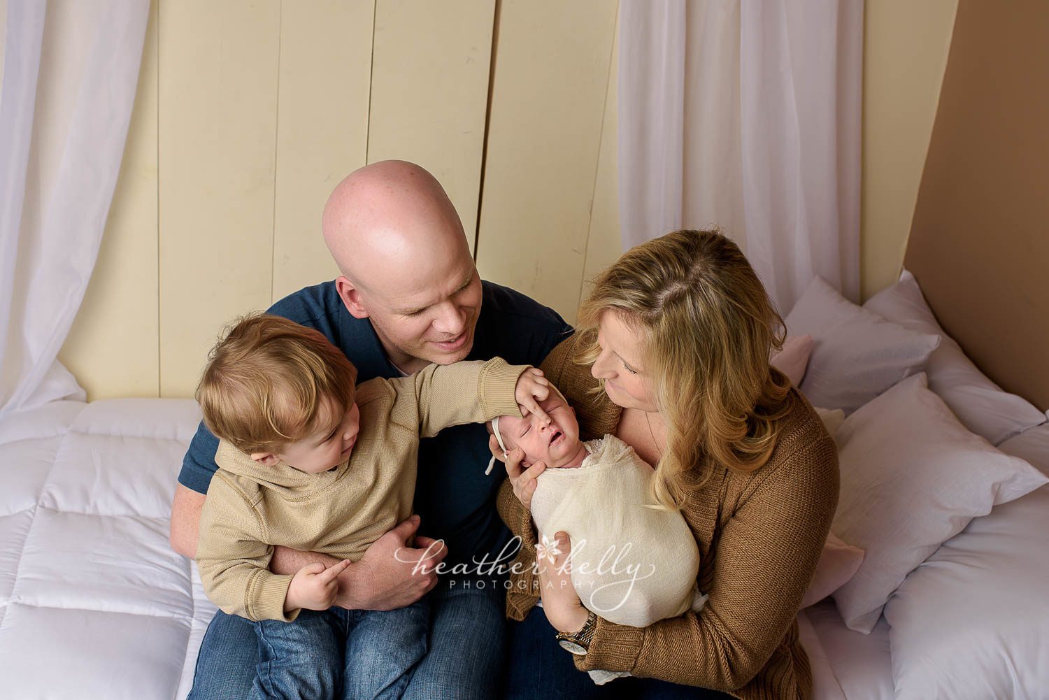 mom, dad, big brother, and baby sister sitting on bed during newborn photography session. trumbull ct newborn photography