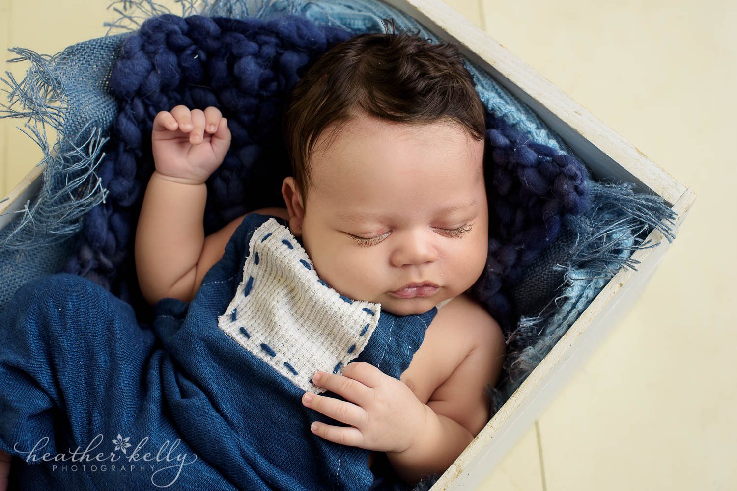 baby boy in romper and crate. danbury newborn portraits