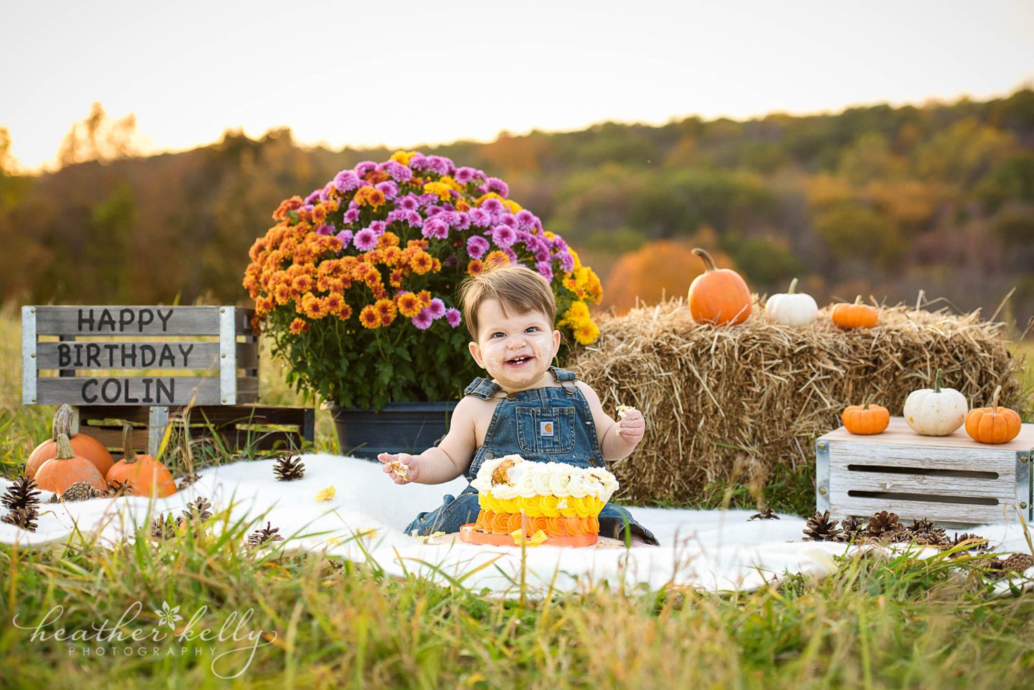 smiling one year old during his fall themed outdoor cake smash. 