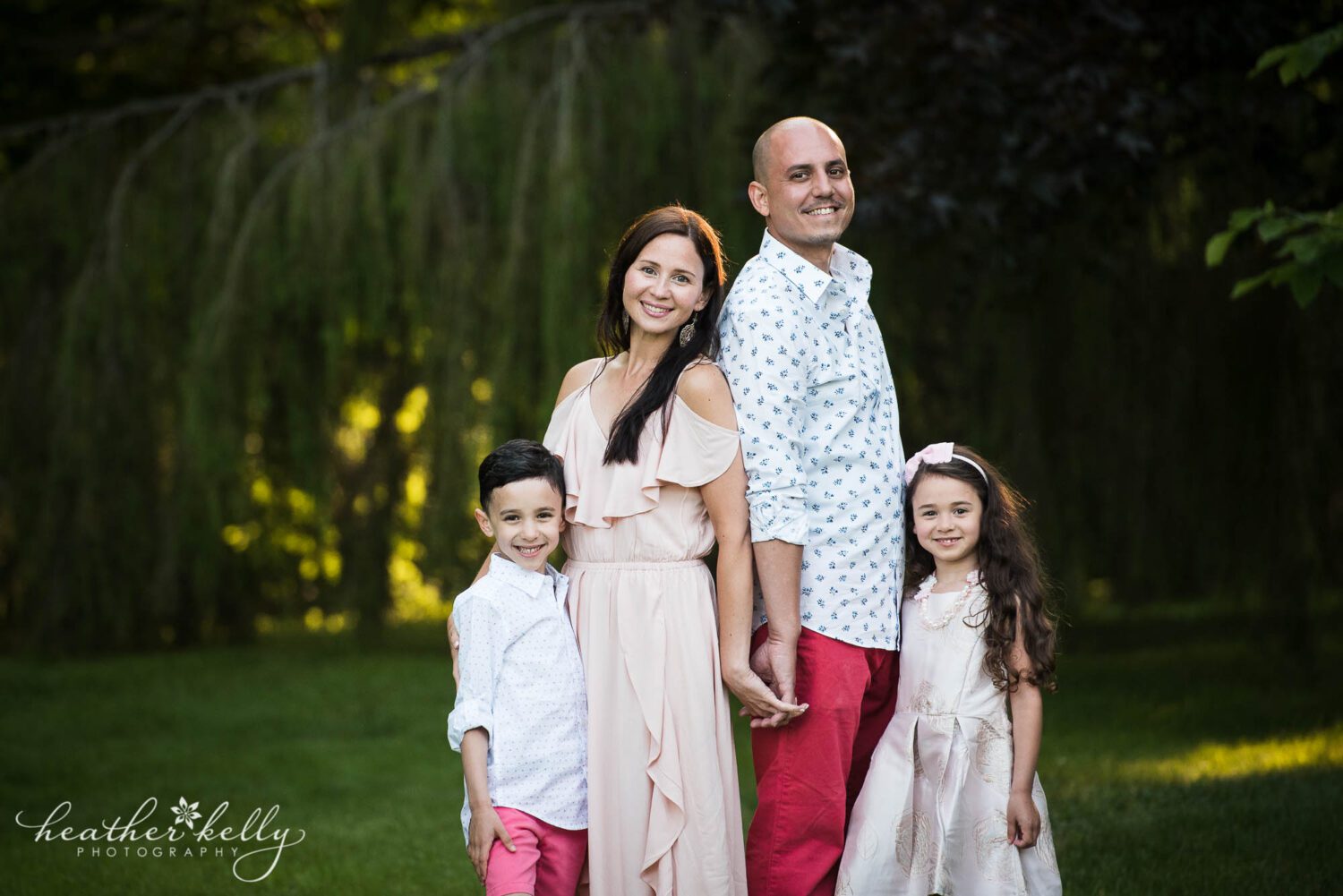 a family of four stand close together and hold hands during their monroe ct family photography session