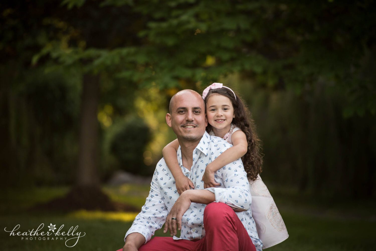 a father squats while his daughter is behind him, handing her arms over his shoulders during their monroe ct family photography session