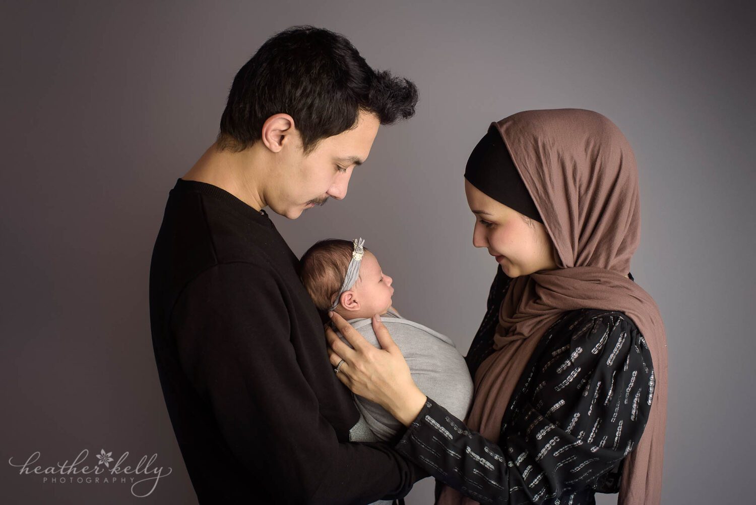 newborn family photography Mom and dad facing each other while holding their newborn baby girl