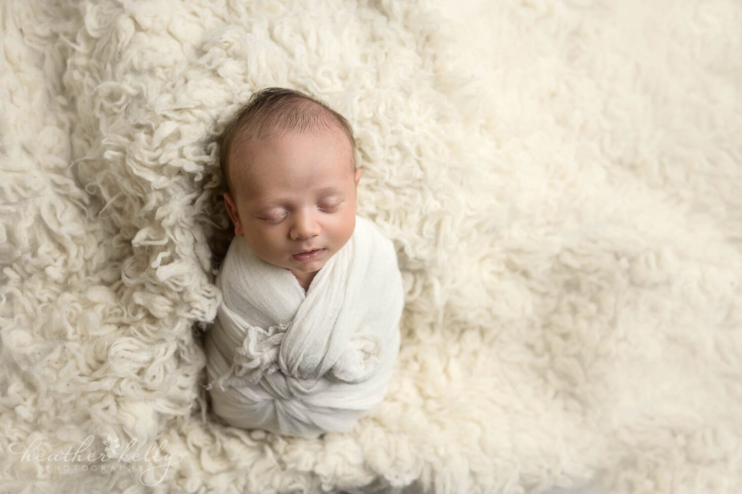 Danbury CT newborn boy photography session. Baby boy is wrapped in white and on a white flokati