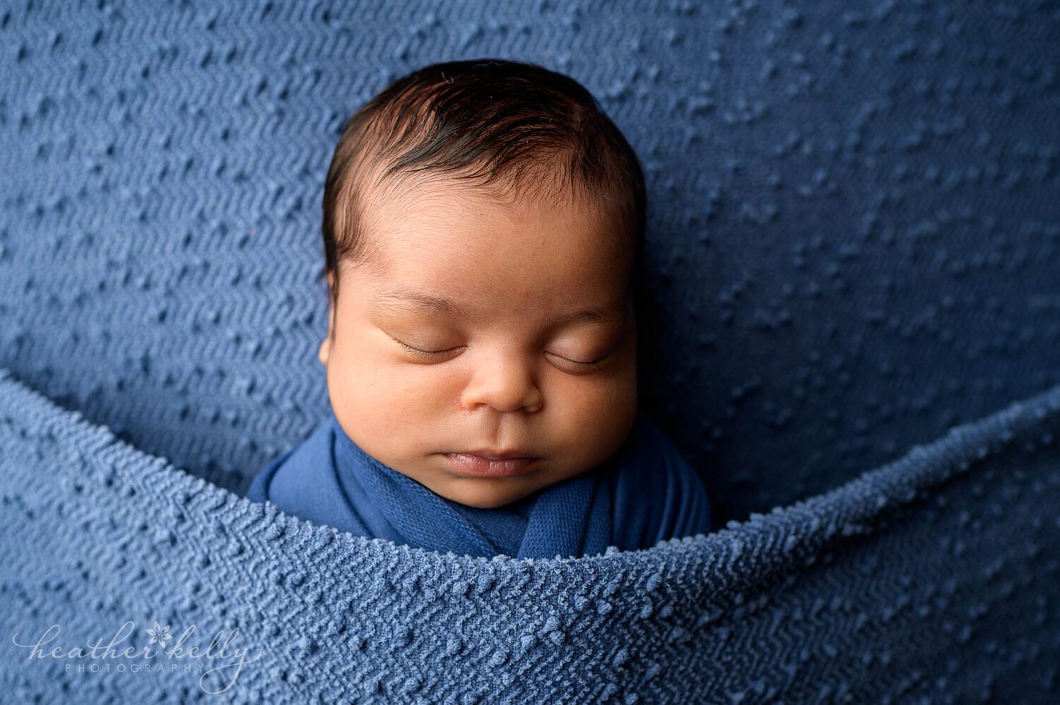 A newborn baby boy posed on a blue blanket. He is sleeping for his newtown ct newborn portrait photography session. 