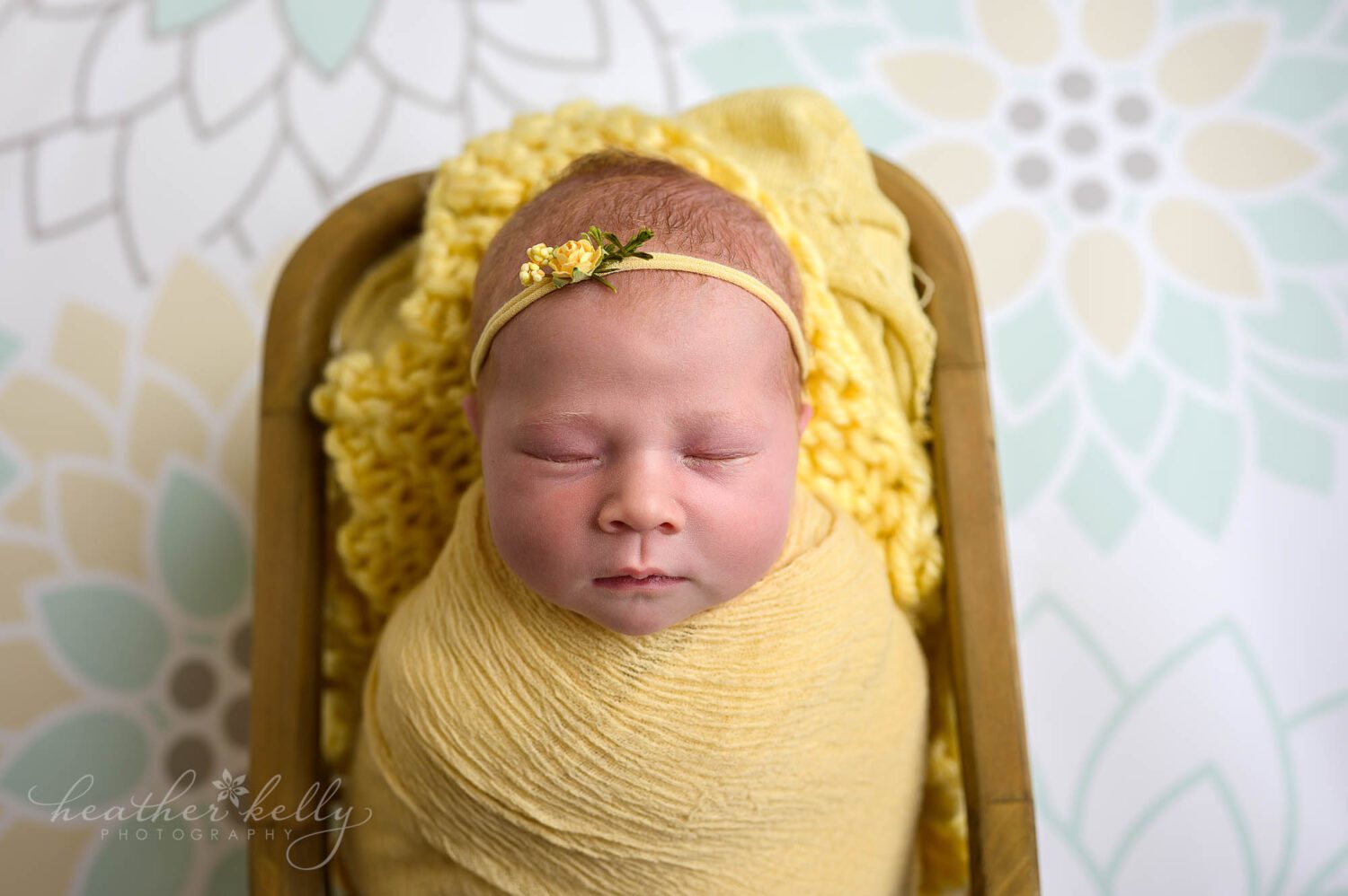 a newborn photography session with a baby girl wrapped in yellow. 