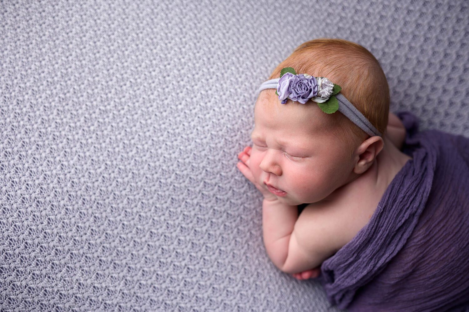 a cozy newborn in purple is asleep during her newborn photography session in ct 
