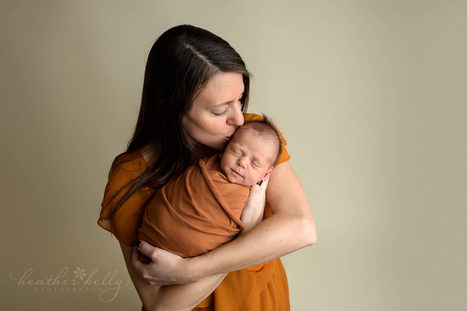 mom holding newborn and kissing his forehead during his connecticut newborn photos