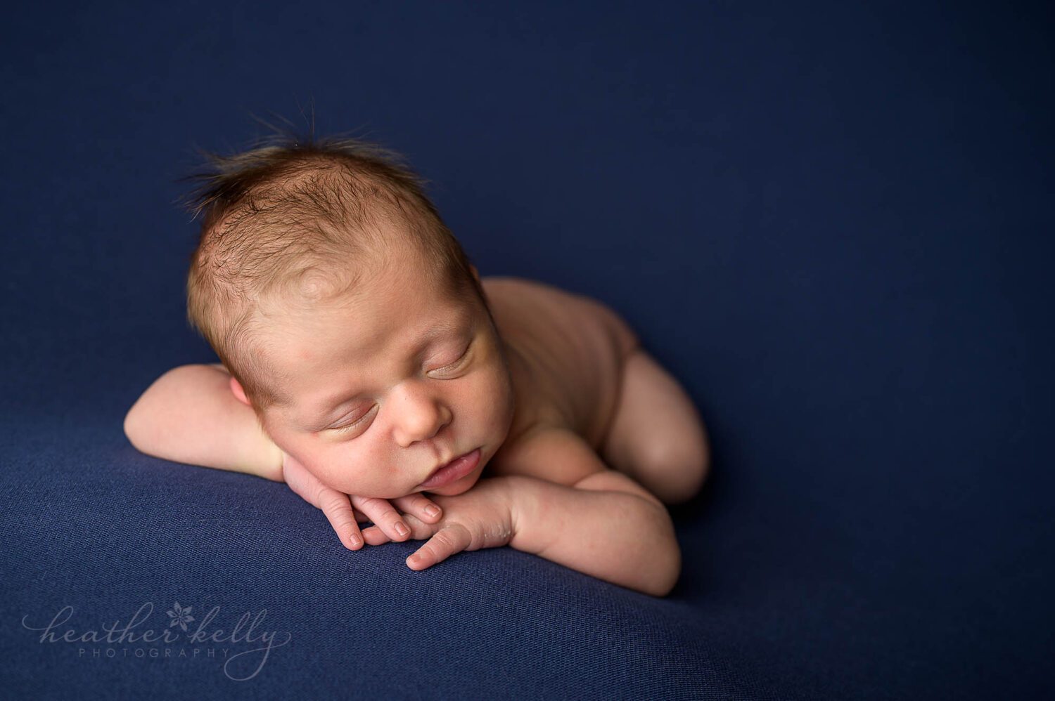 a newborn boy sleeping on a blue backdrop during his newborn photography session 