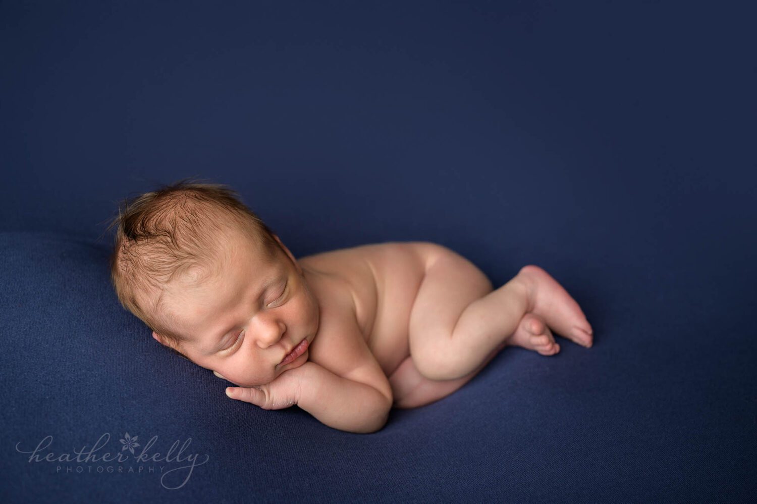 a connecticut newborn sleeping all cozy on a blue backdrop