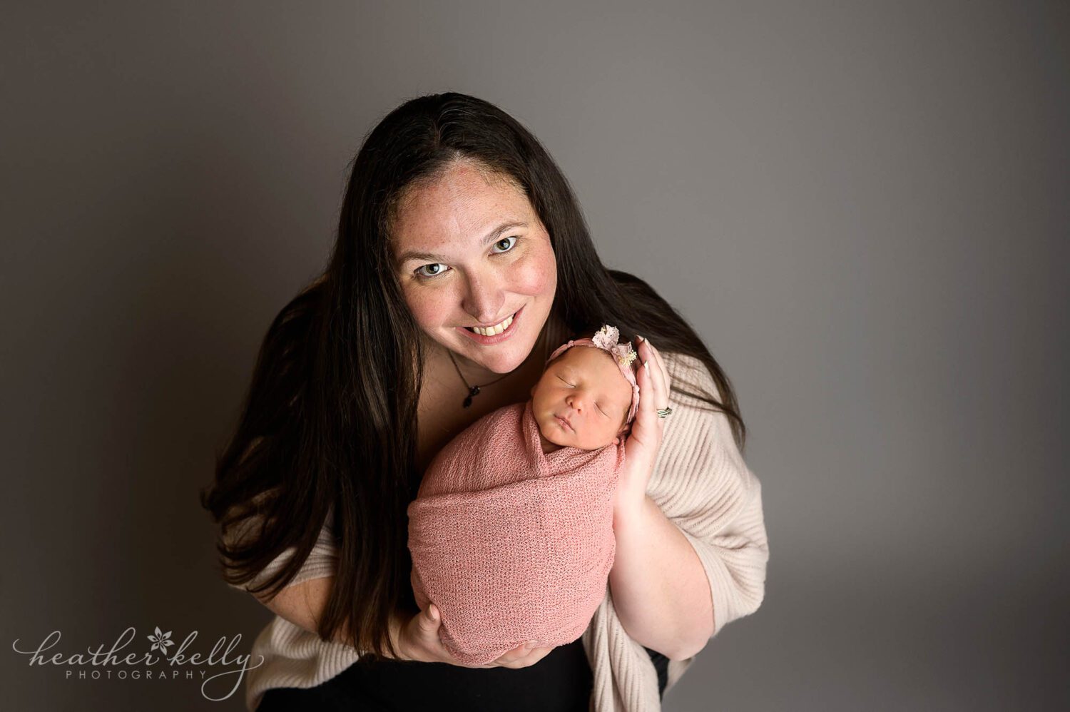 a mom holds her newborn daughter during a ct newborn photography session. 