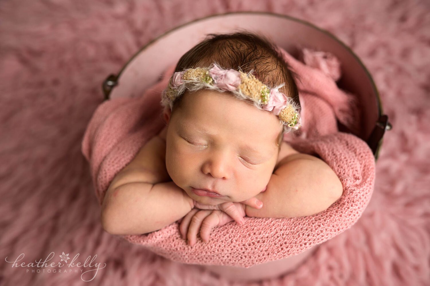 a newborn girl is sleeping in a pink bucket. 