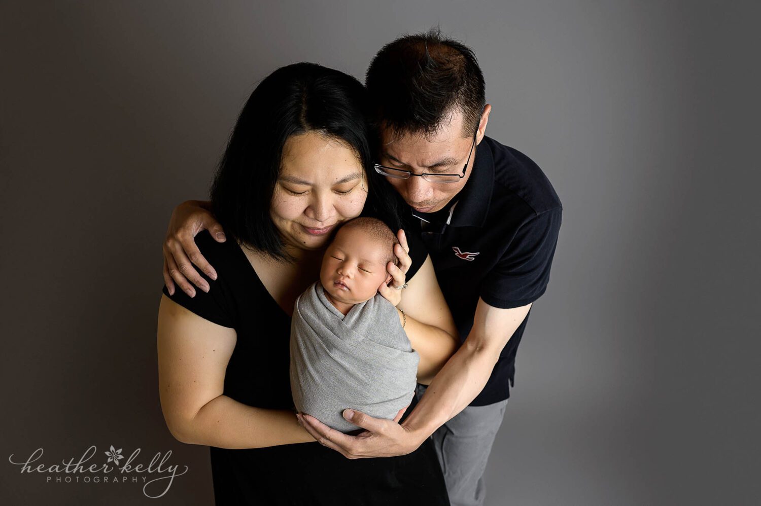 mom and dad hold their newborn boy and look down at him during a newborn studio session in Newtown ct 