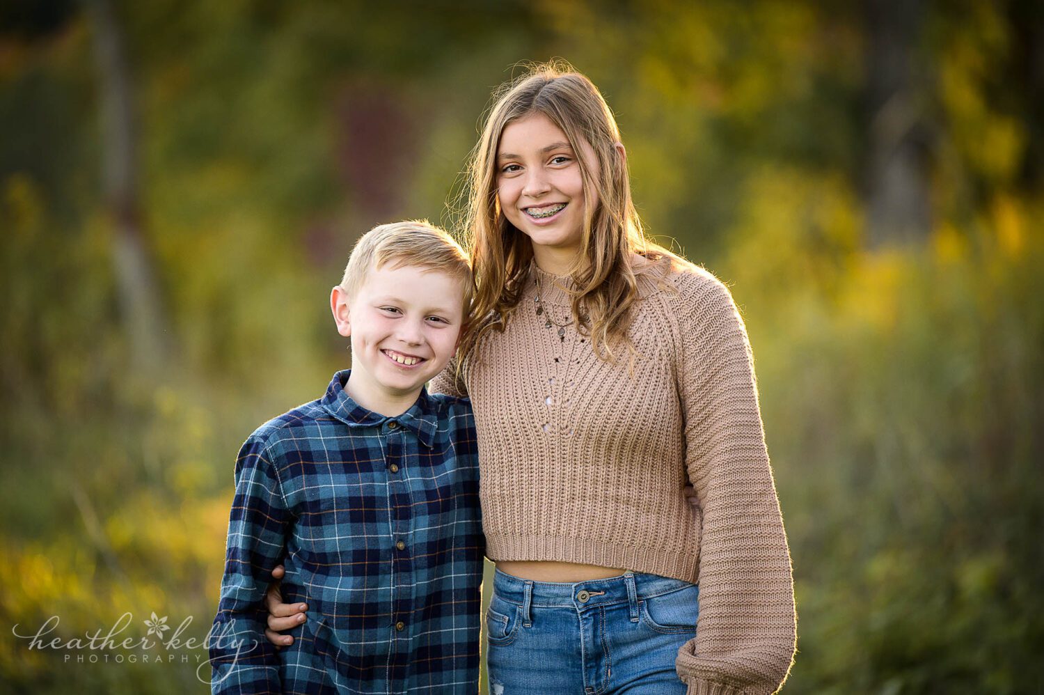 a brother and sister smiling and looking at the camera during a family session