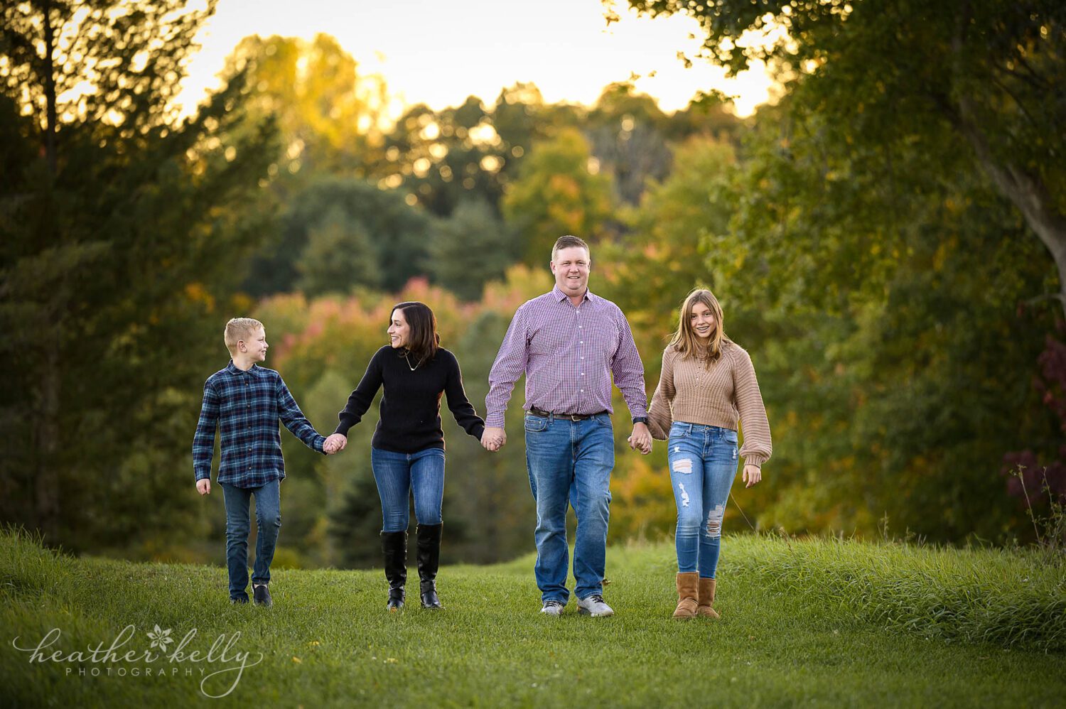 a family of 4 holds hands while walking together during a 2023 family photo session. 