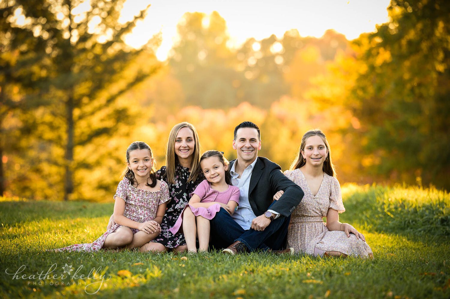 a Ridgefield CT family photography session. A family of 5 sits on the grass smiling. 