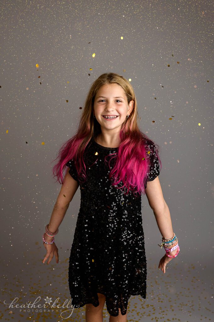 a girl with pink hair has fun throwing gold glitter during a mini session in ct