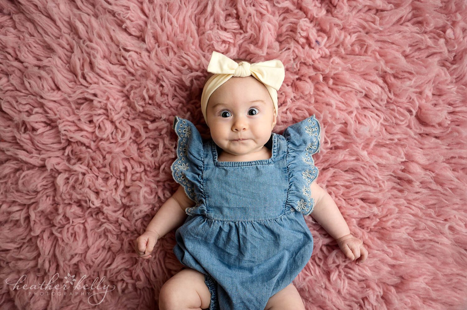 a 3 month old looks at the camera on a pink rug
