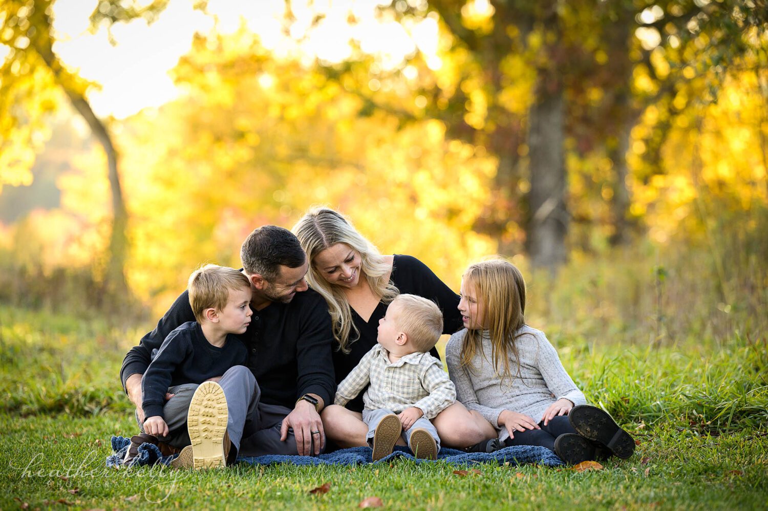a family mini session in newtown ct. A family of 5 all looks at each other while siting on a blanket. 