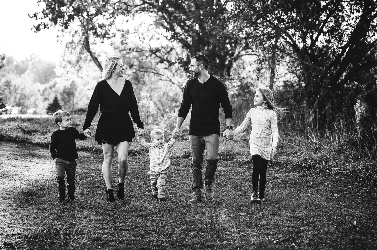 a family of 5 holds and walks during their family photography session. 